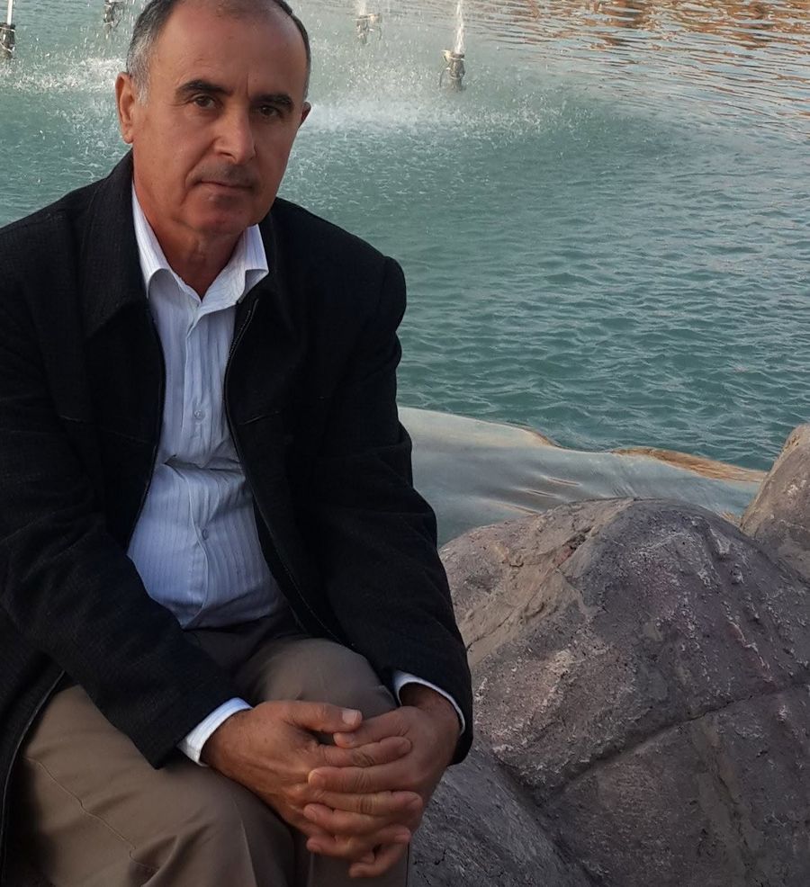 Yonan Roil seated on the rocks beside a fountain pool